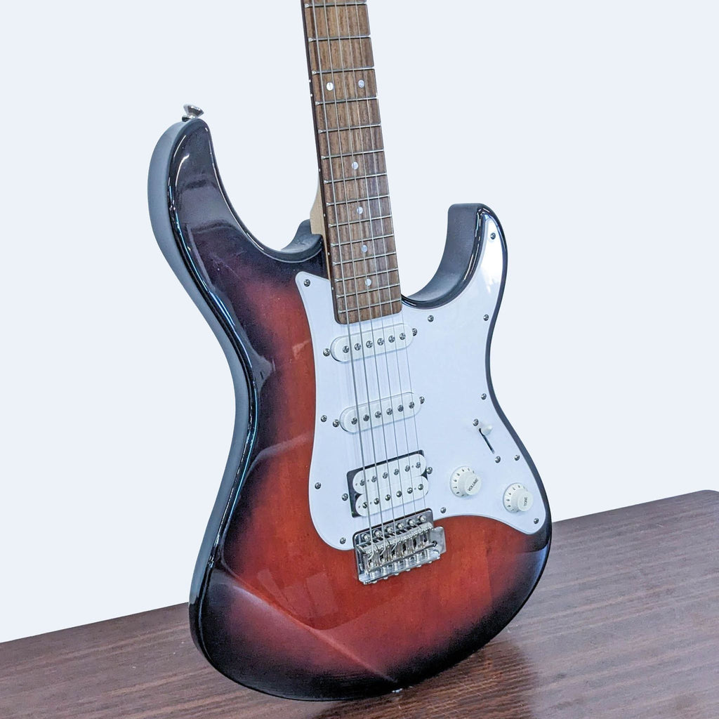 Close-up of Yamaha guitar showing three single-coil pickups and white pickguard against sunburst body.