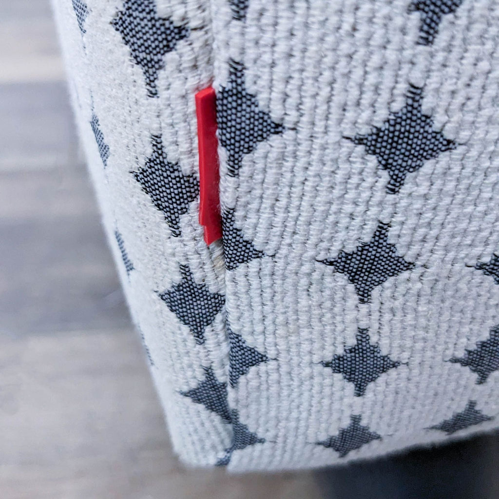3. Close-up of EQ3 chair's upholstery showing geometric pattern and a red EQ3 tag on side seam.