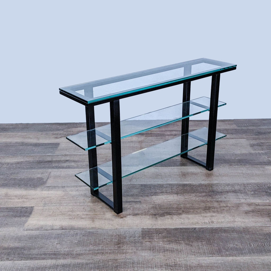 Angled view of a Crate & Barrel glass and metal side table showcasing the tiered glass shelves and sturdy frame design.