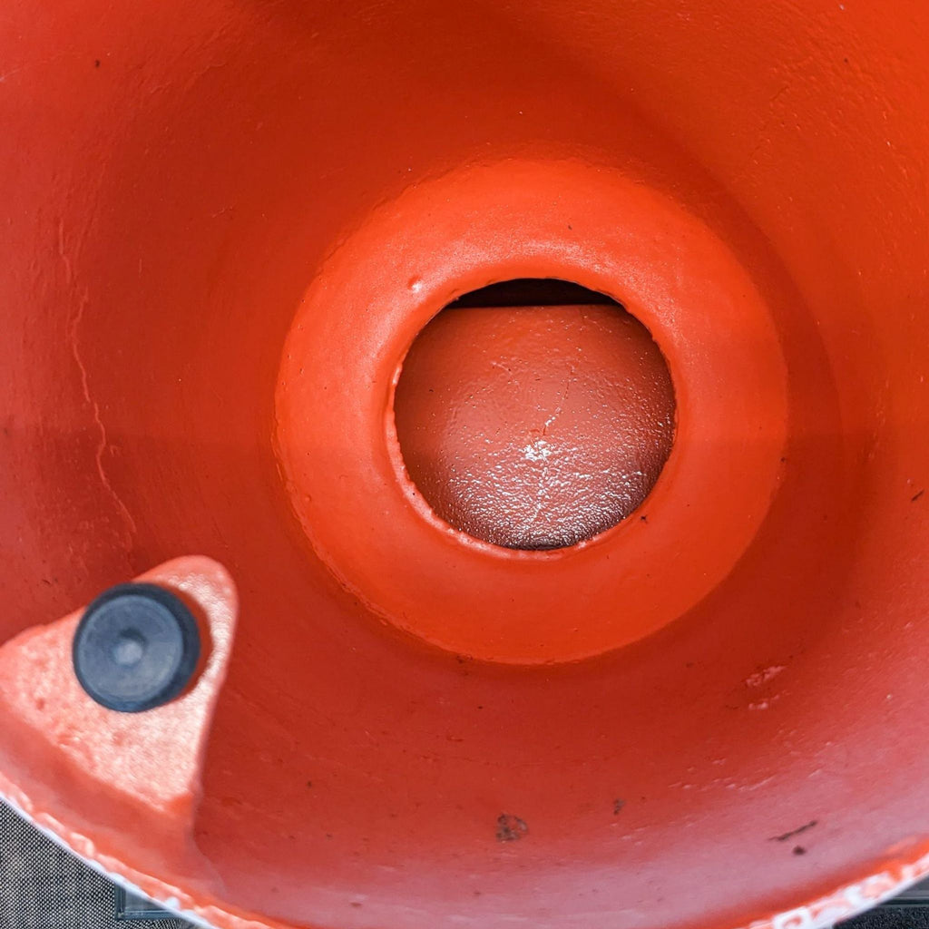 2. Close-up view of the orange-colored underside of a West Elm aluminum table showing a central circular opening and mounting point.
