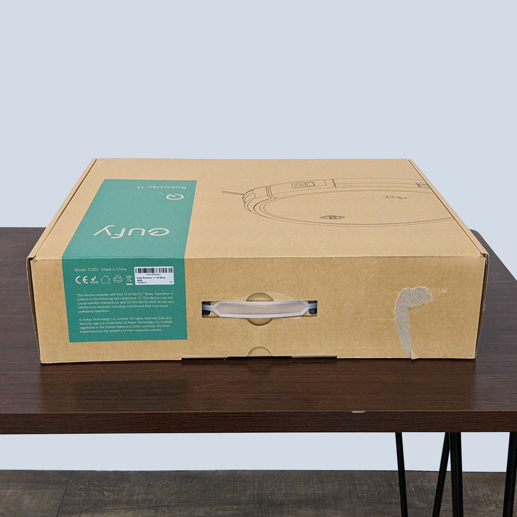 Eufy RoboVac vacuum cleaner's box on a table, highlighting model number and secure packaging.