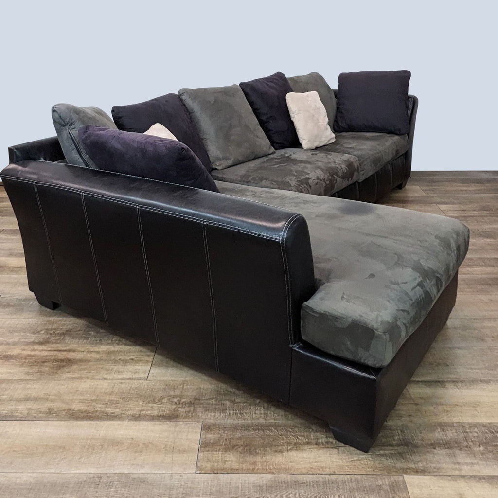 Angled view of Ashley Furniture's Jacurso sectional, with dark pleather framing and contrasting grey cushioning.