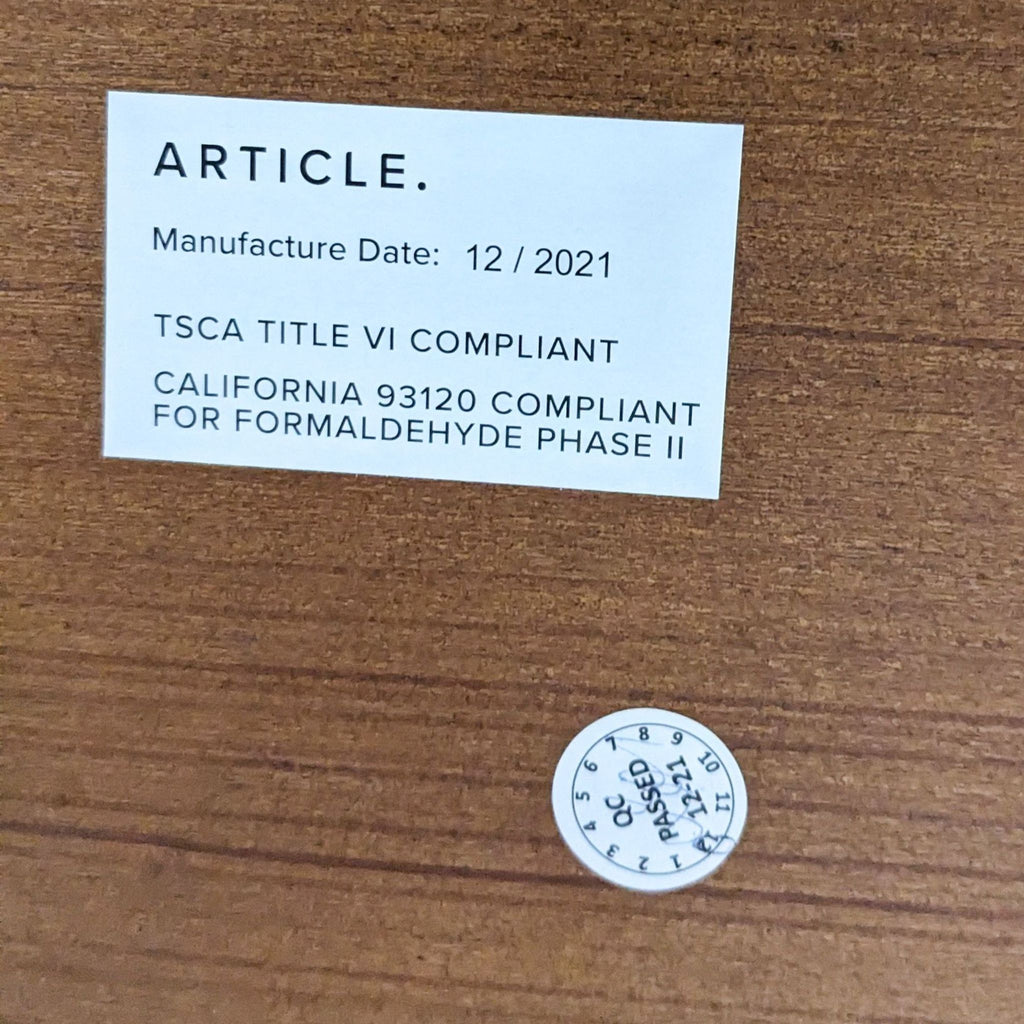 Label on the Conan Dining Table by Article showing manufacture date and compliance info.