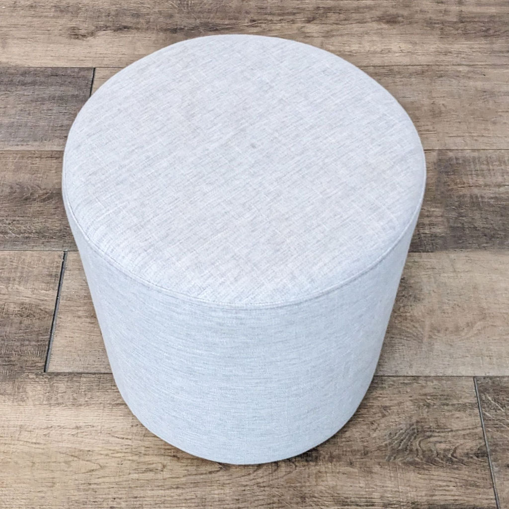 2. "Article brand circular upholstered stool in pale blue positioned on wooden flooring."