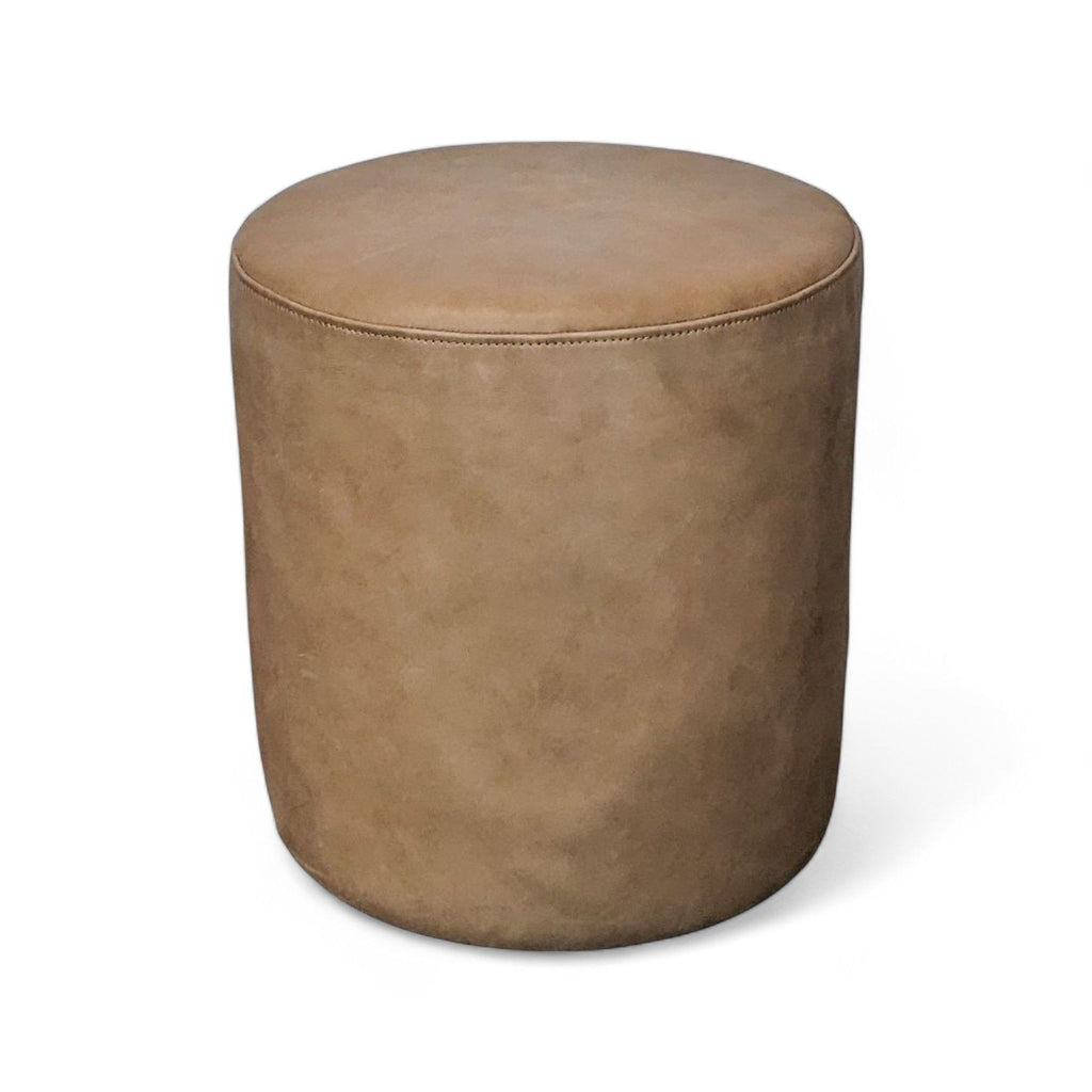 Tan leather ottoman by Article, round and versatile for seating or table use.