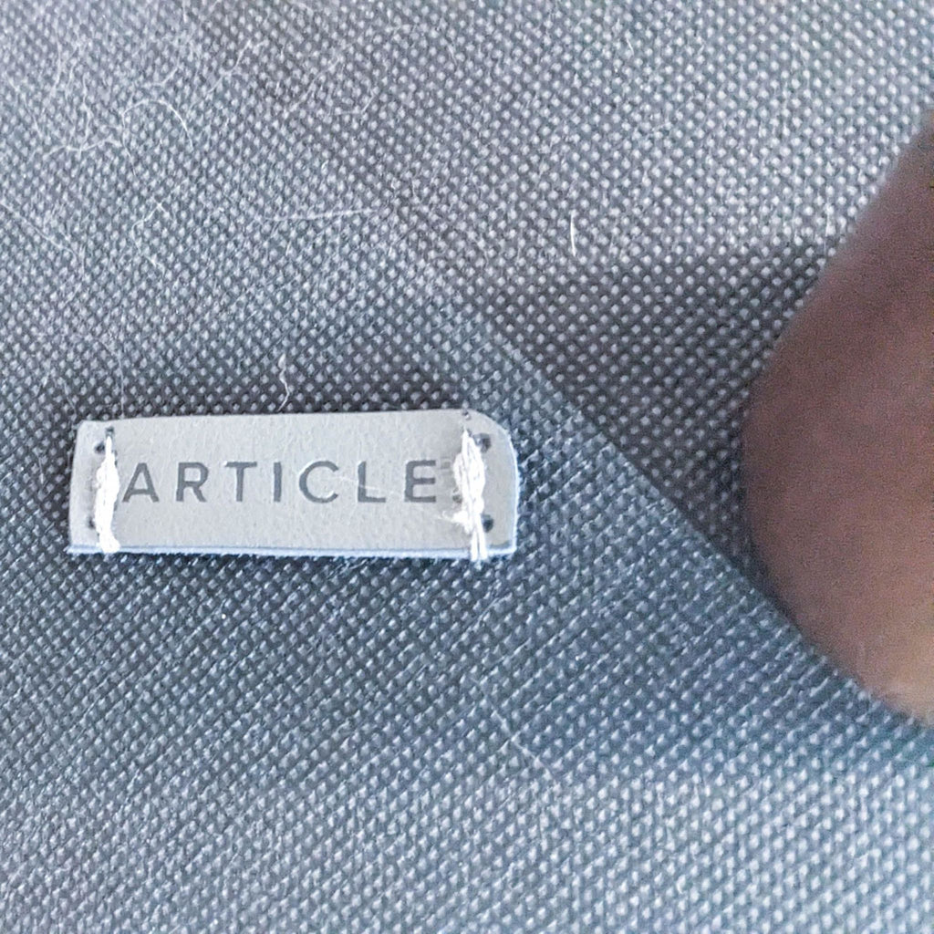 3. Close-up of the ‘Article’ brand logo on a silver tag attached to a textured fabric, indicative of product branding.