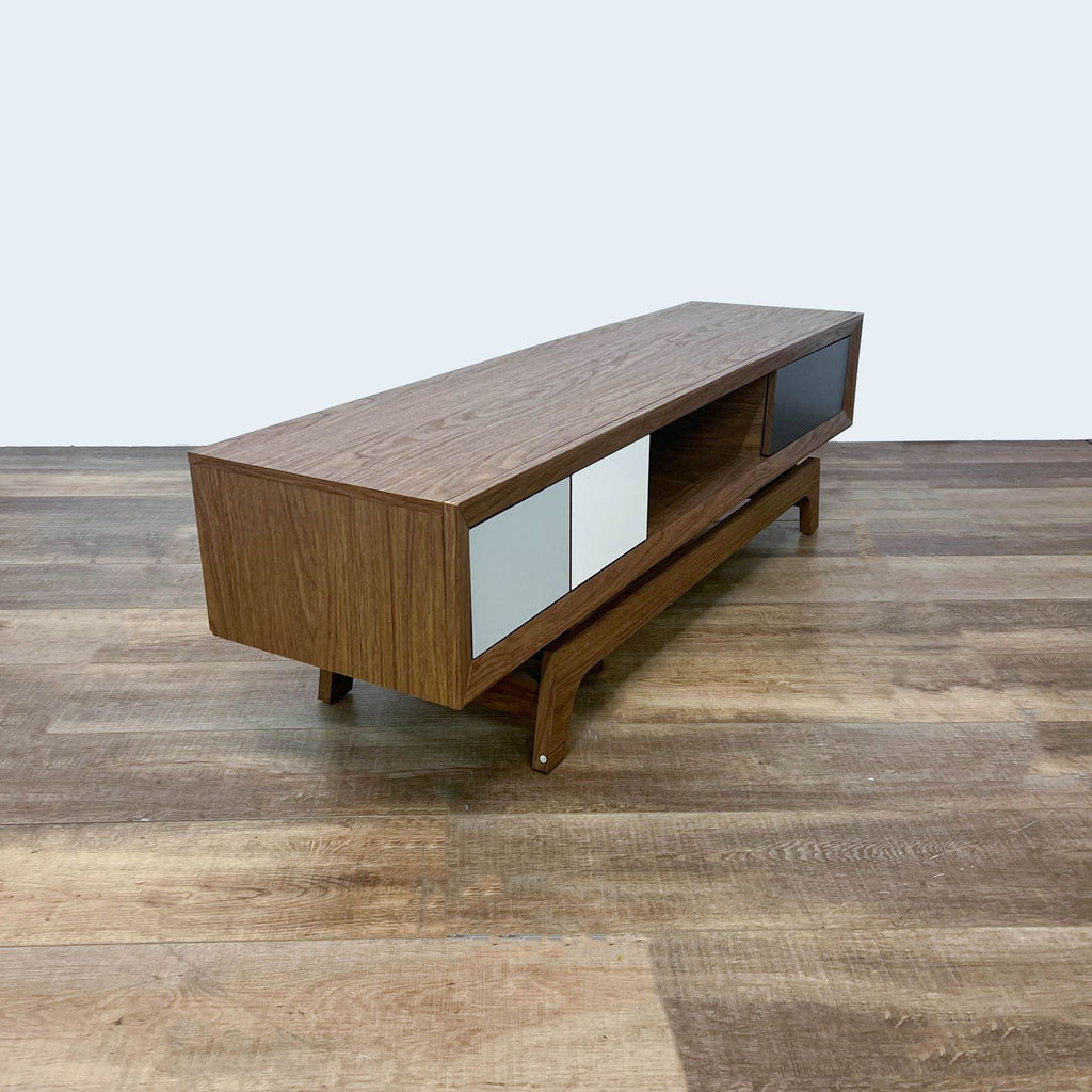 Angled view of a Baxton Studio mid-century modern entertainment center with white and black drawers on a wooden base.