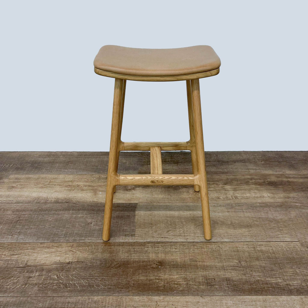 Front-facing solid oak stool featuring upholstered tan leather seat from Article.