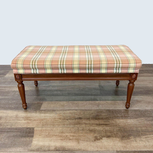 Ethan Allen carved wooden bench with plaid padded seat, 43 inches long, on a wood floor.