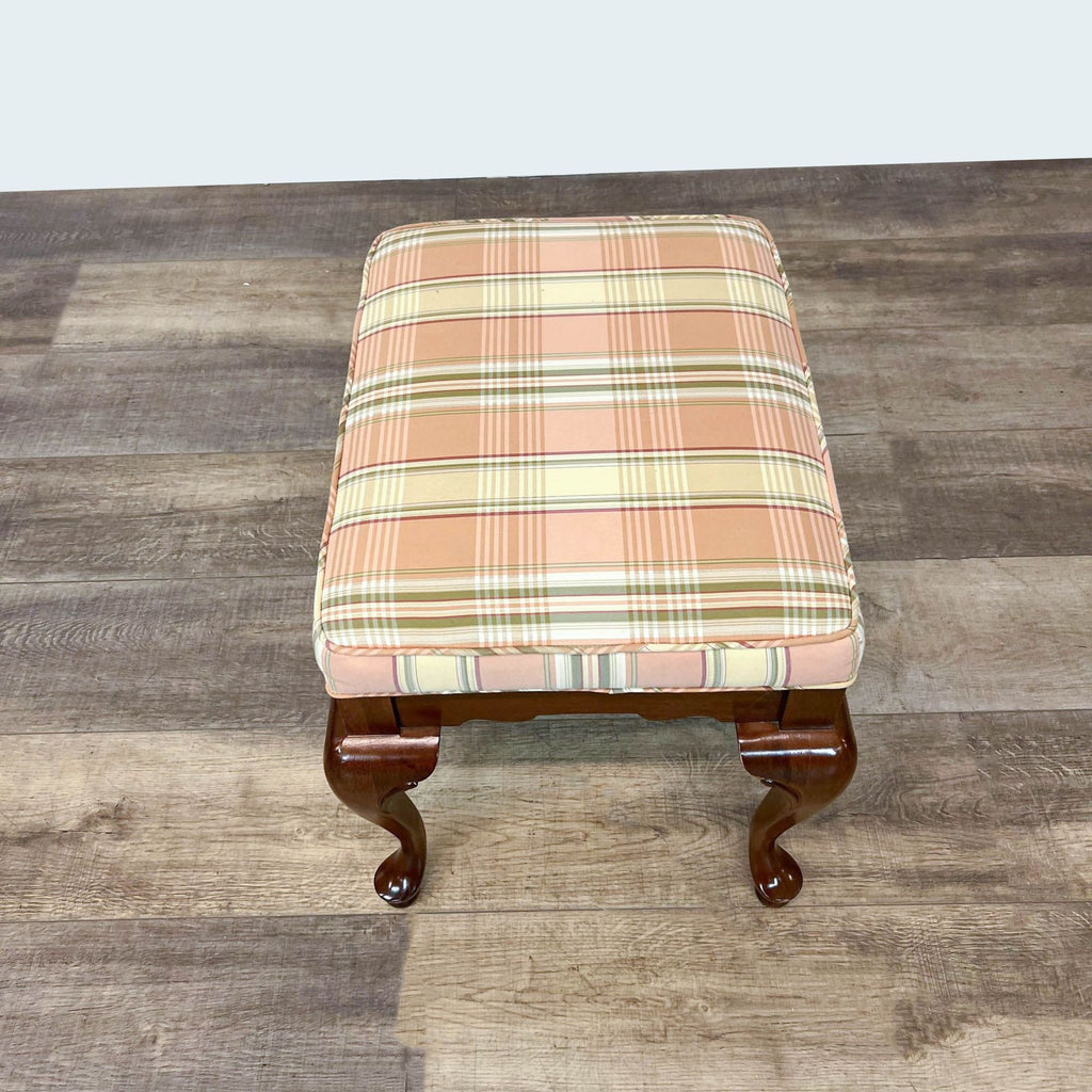 Wood frame bench with checkered fabric, Reperch brand, Queen Anne design, on a wooden floor.