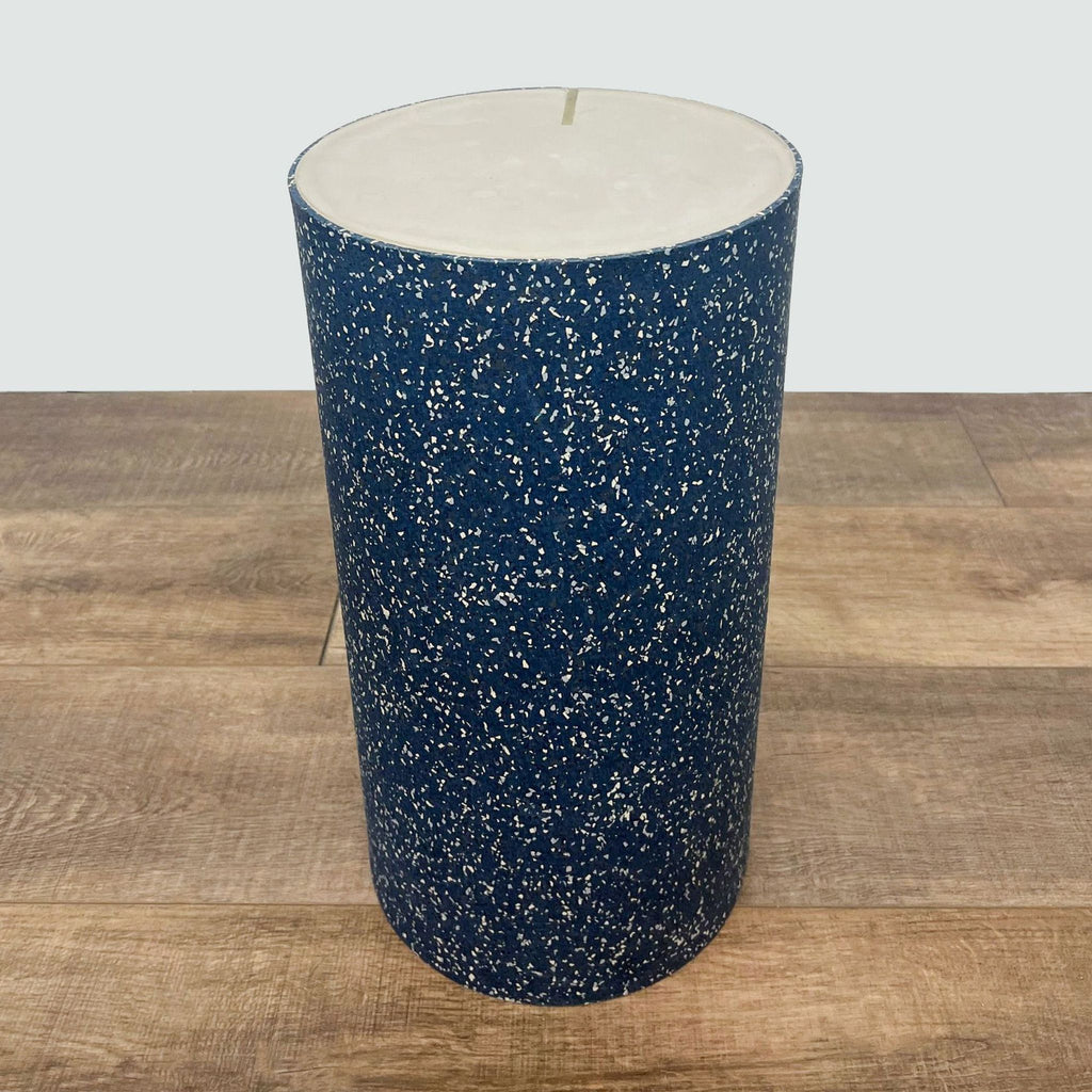 Cylindrical Reperch side table with rubberized blue terrazzo design on a wood floor.