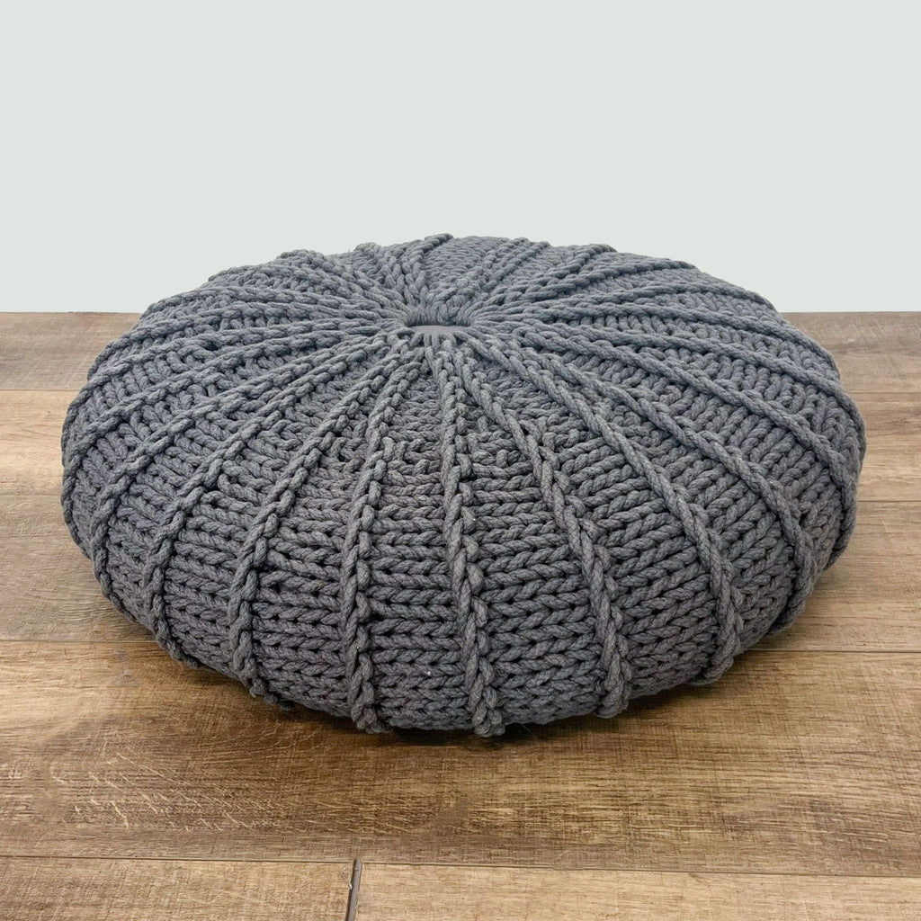 3. Handcrafted grey Reperch pouf ottoman displayed from above, highlighting the knitted ridges and centerpiece.