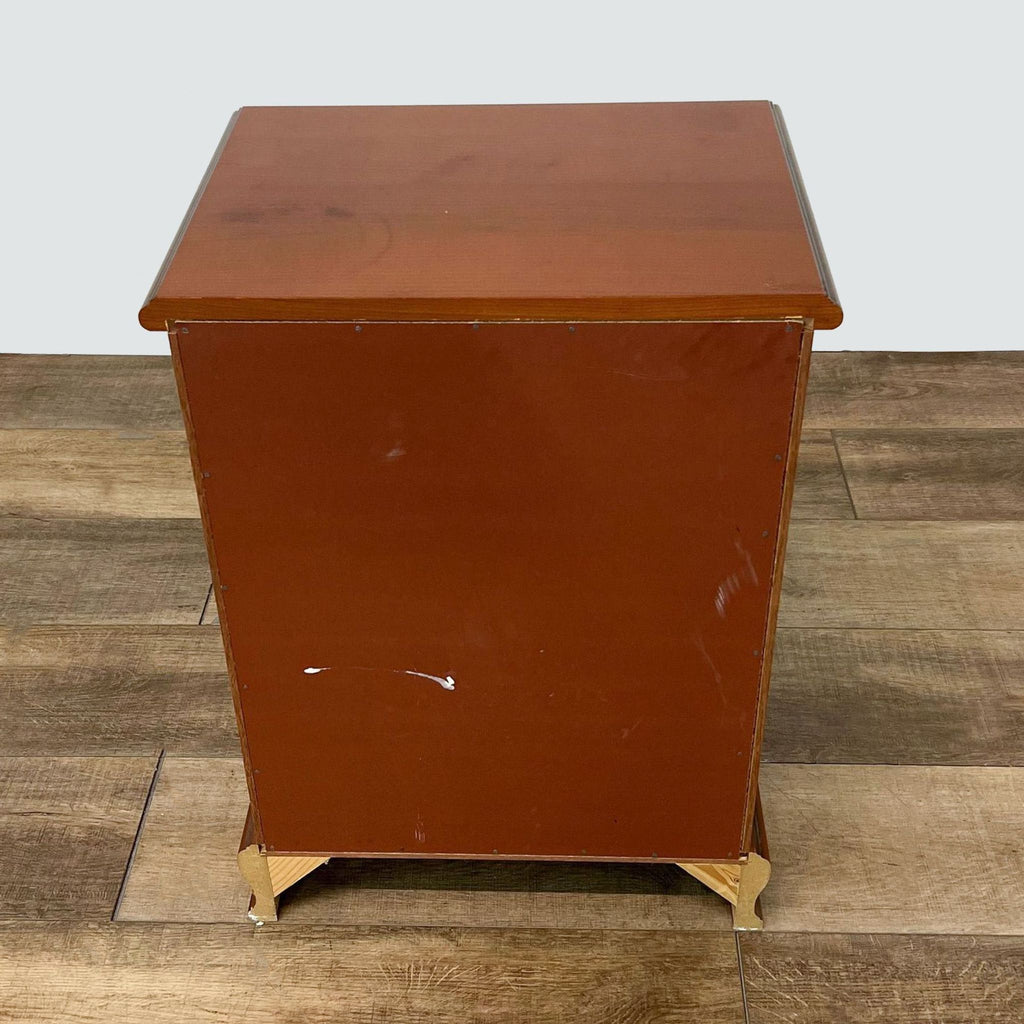 Back view of Reperch end table displaying solid wood construction and simple design on wooden flooring.