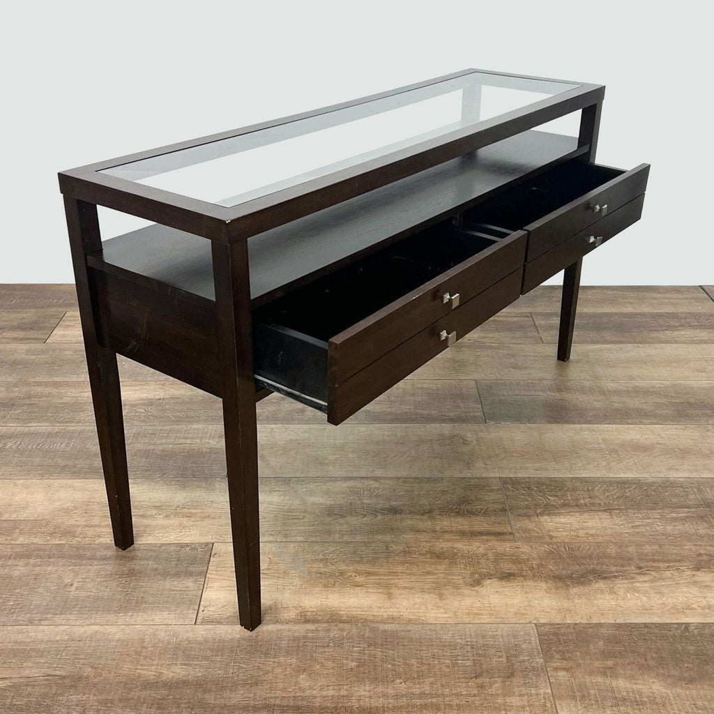 Open drawers of a Reperch wooden side table with glass top on wood-patterned flooring, showcasing storage space.
