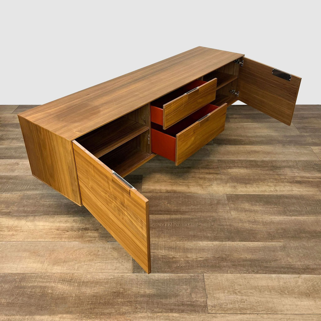 Interior view of a Blu Dot entertainment center with walnut veneer, showcasing open drawers with orange interiors.