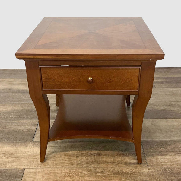 Thomasville end table with inlaid top design, single drawer, lower shelf, and cabriole legs on a wooden floor.