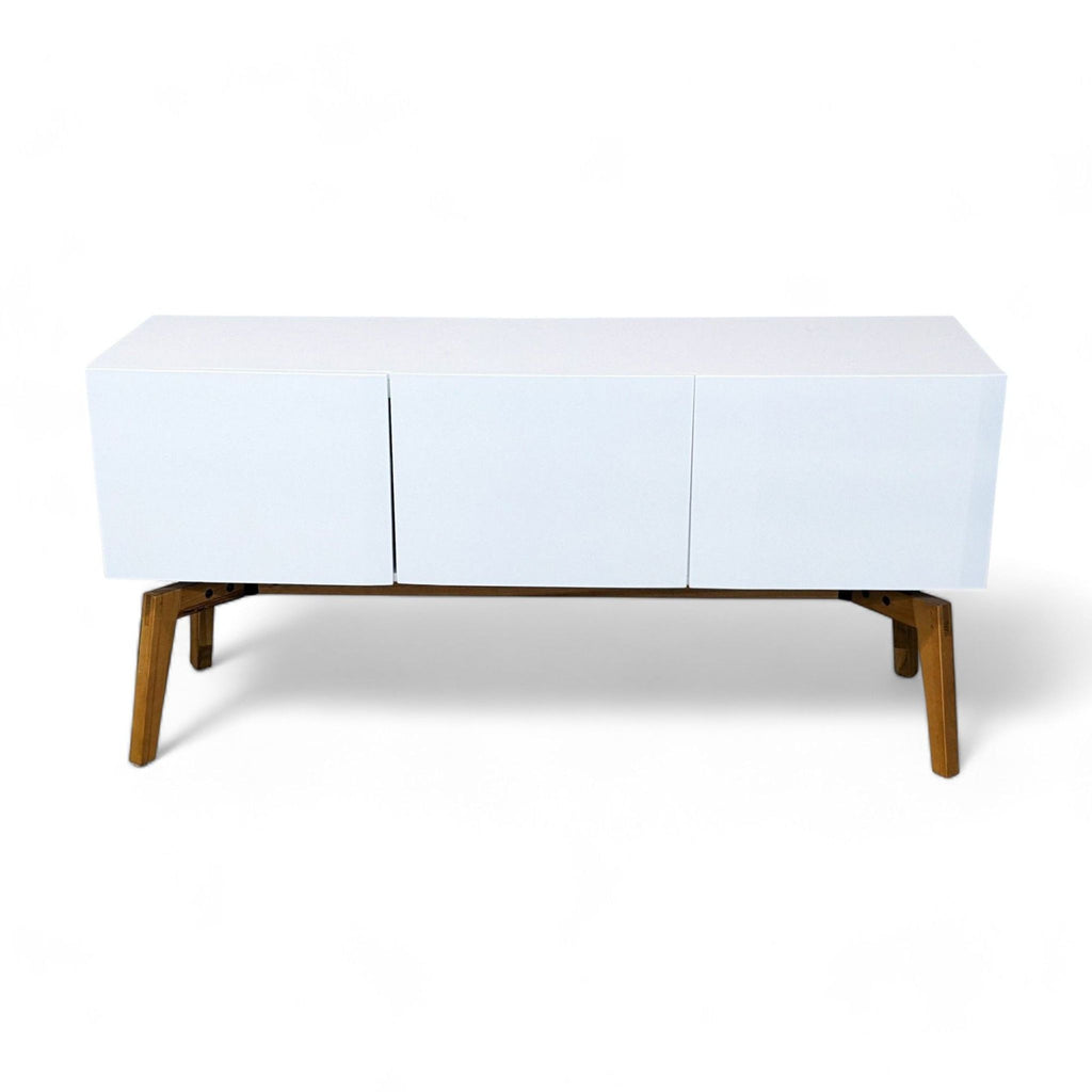 1. White CB2 entertainment center with asymmetrical 3D ridge details and abstract handles, atop walnut-finish tapered legs.