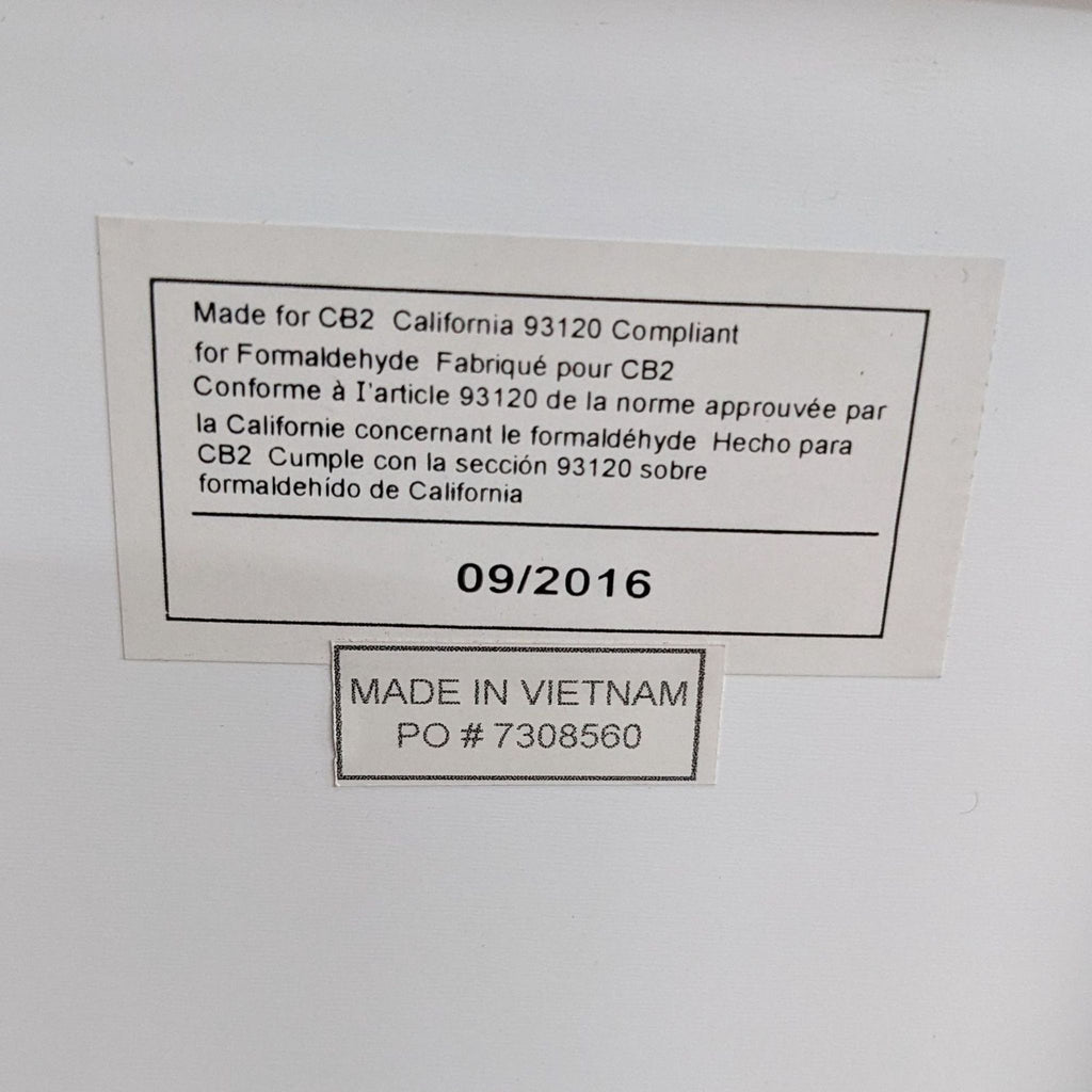 3. Close-up of a label on a white entertainment center indicating it's made for CB2, compliant with California formaldehyde standards, and manufactured in 09/2016.