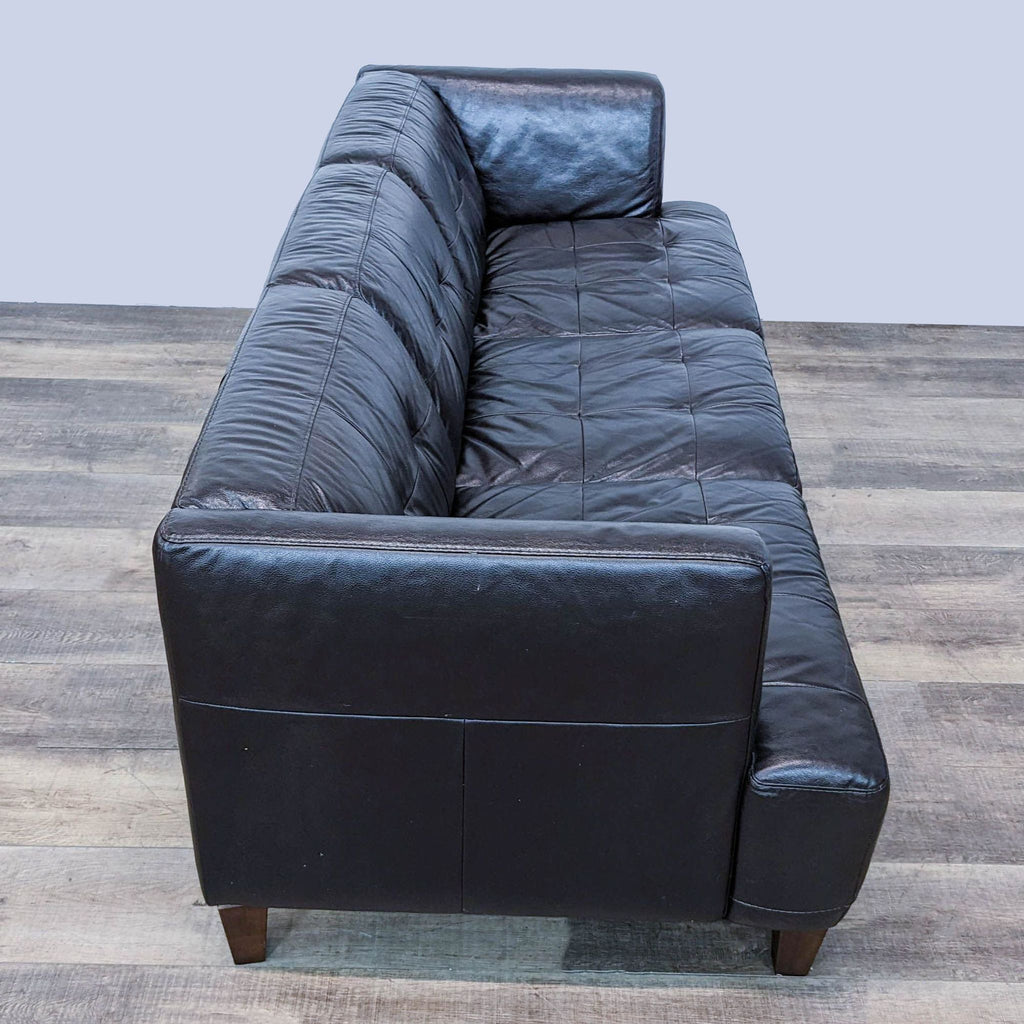 Rear view of a high-quality brown leather Chateau d'Ax 3-seat sofa on a wooden floor.