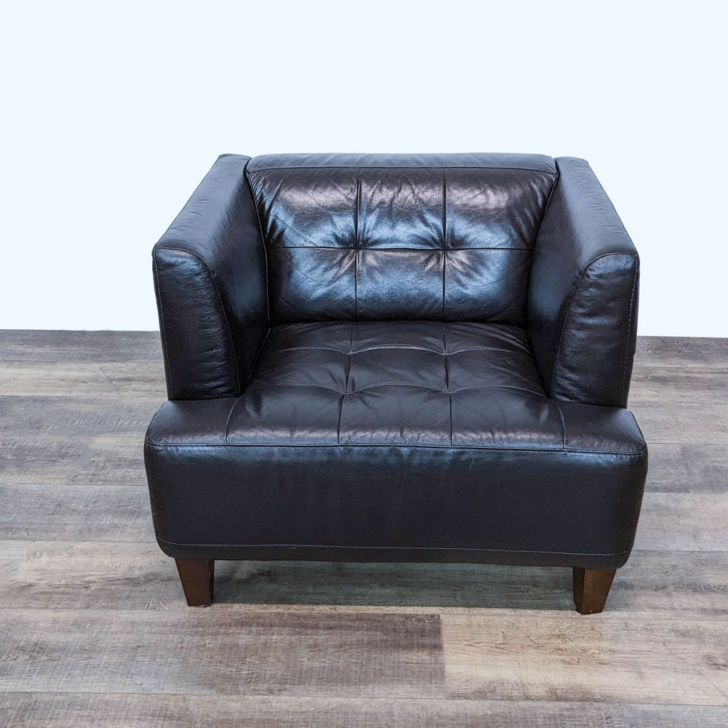 Premium Chateau d'Ax brown leather armchair with tufted cushion and wooden legs, front view on wood floor.