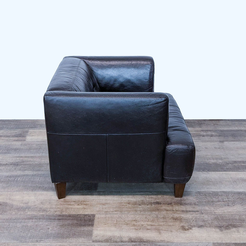 Side view of a Chateau d'Ax brown leather armchair with plush back and stable wooden legs, showcasing design details.