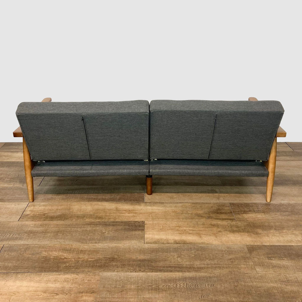 Rear view of 3-seat futon with sturdy wooden legs and grey fabric, showcasing supportive design.
