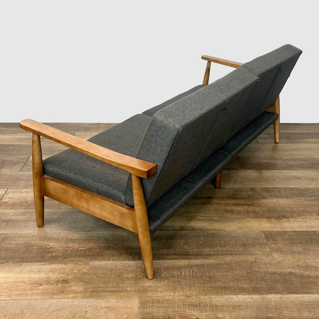 Side angle of split-back futon displaying armrests and grey linen fabric on wooden frame.