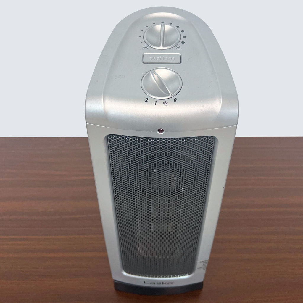 Front view of a sleek Lasko portable ceramic heater with safety features on a wooden surface.