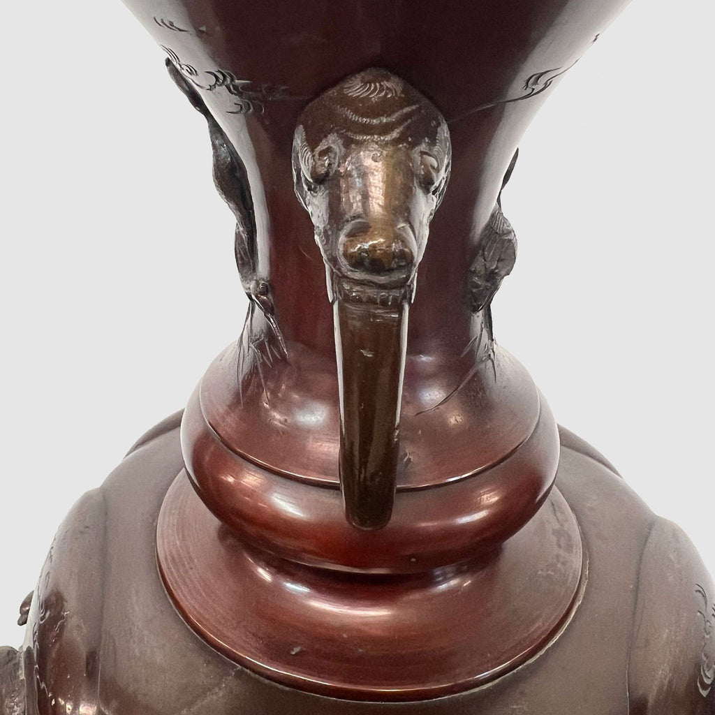 a large chinese bronze lamp with a bird head on a stand.