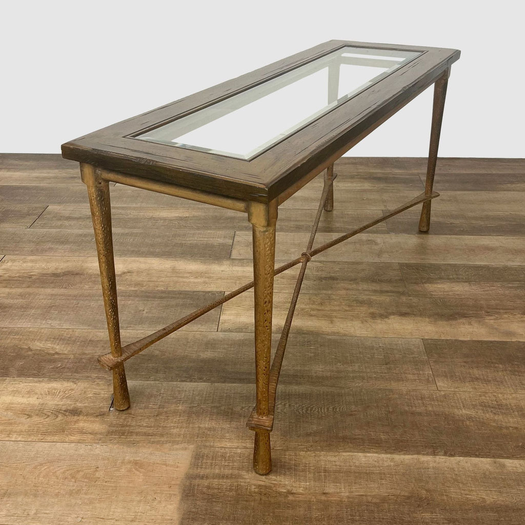 Console table by Reperch featuring a clear glass insert, wooden edges, and forged metal legs on wood-style flooring.