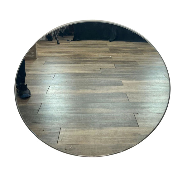 Round Infinity 2D wall mirror by Room & Board on wooden floor with a slim steel frame.