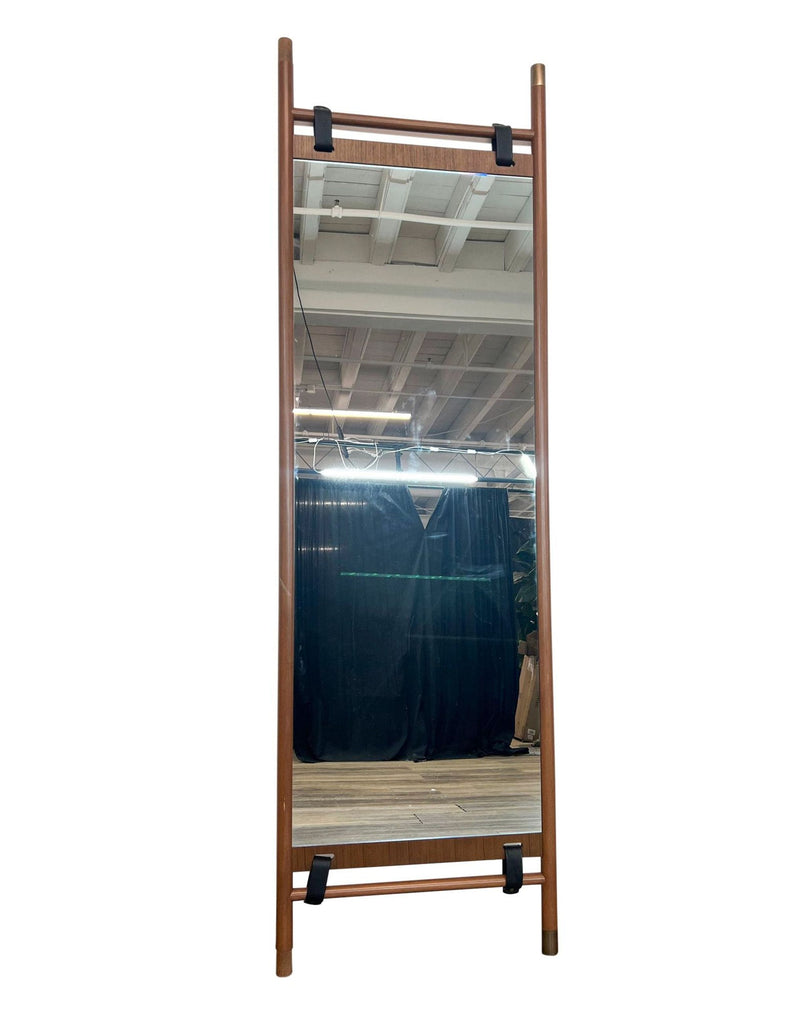 The Beau floor mirror by Article features a walnut frame with leather straps and brass hardware.