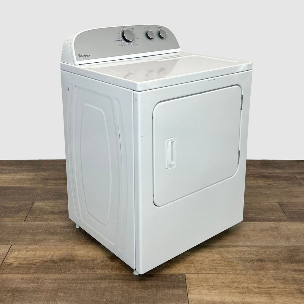 Front angle view of a white Whirlpool Top-Load Washer on a wooden floor, showing user-friendly controls.