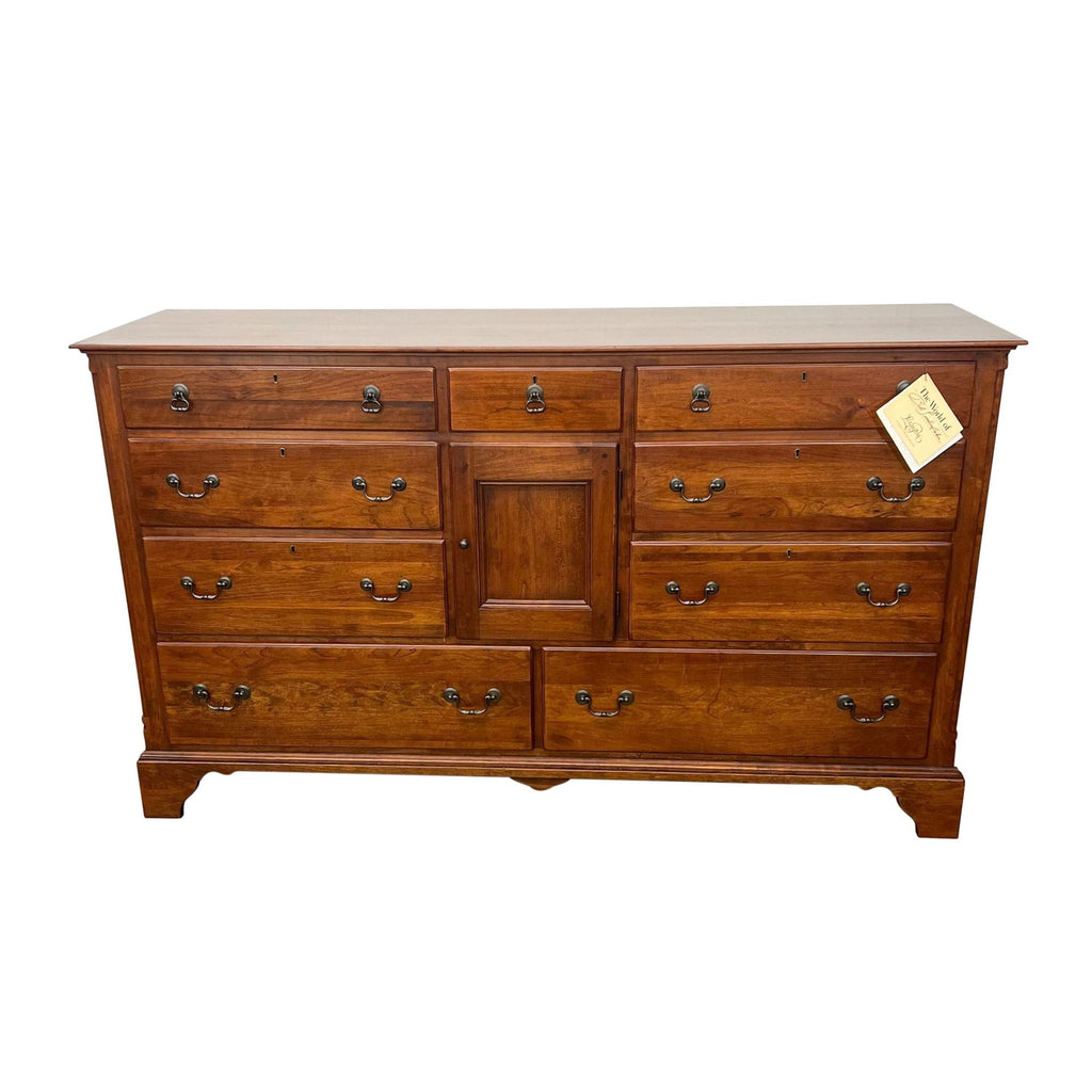 Large cherry wood dresser with nine drawers, central cabinet, and metal hardware.