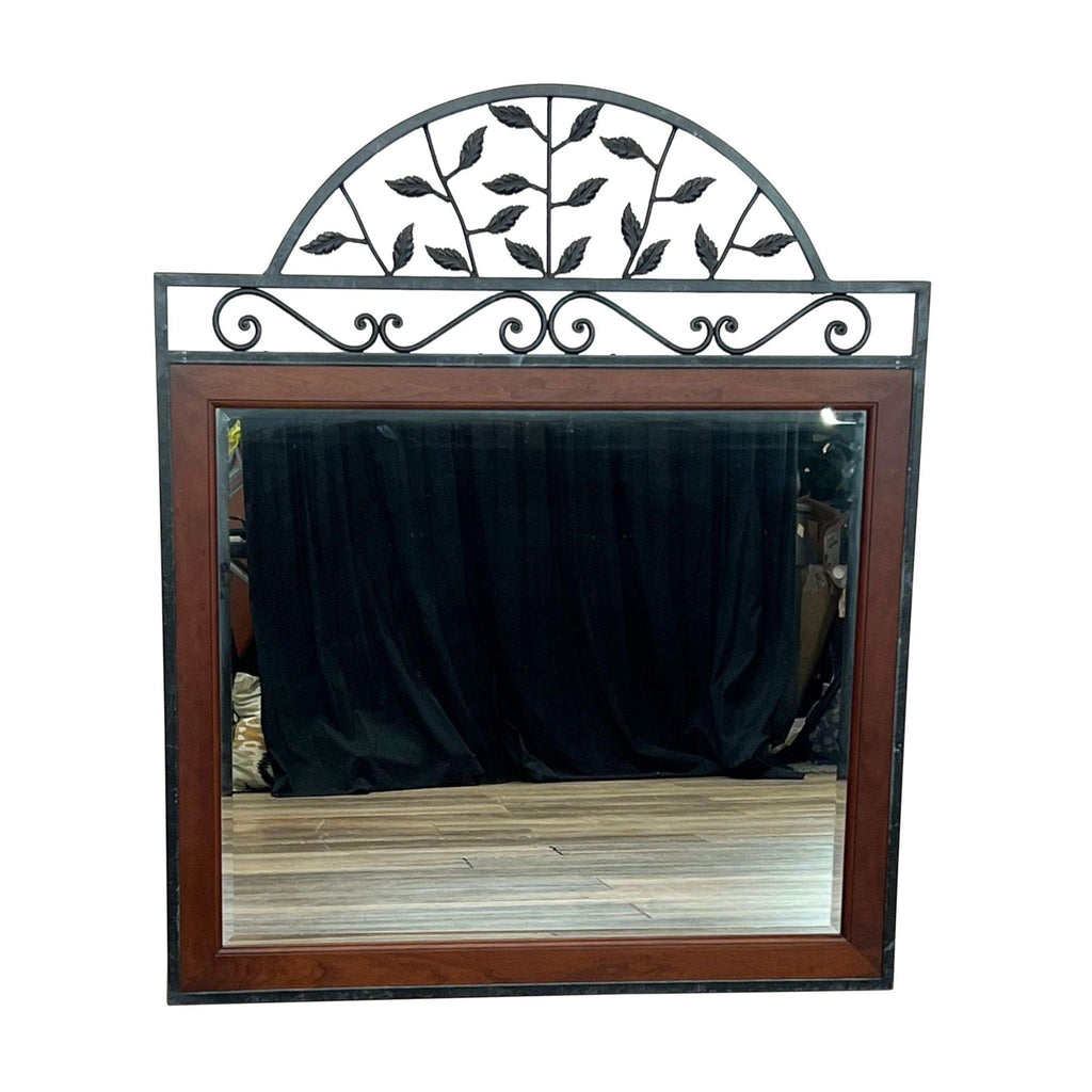 Mirror with cherry wood frame and decorative metal scrollwork featuring leaves and vines.