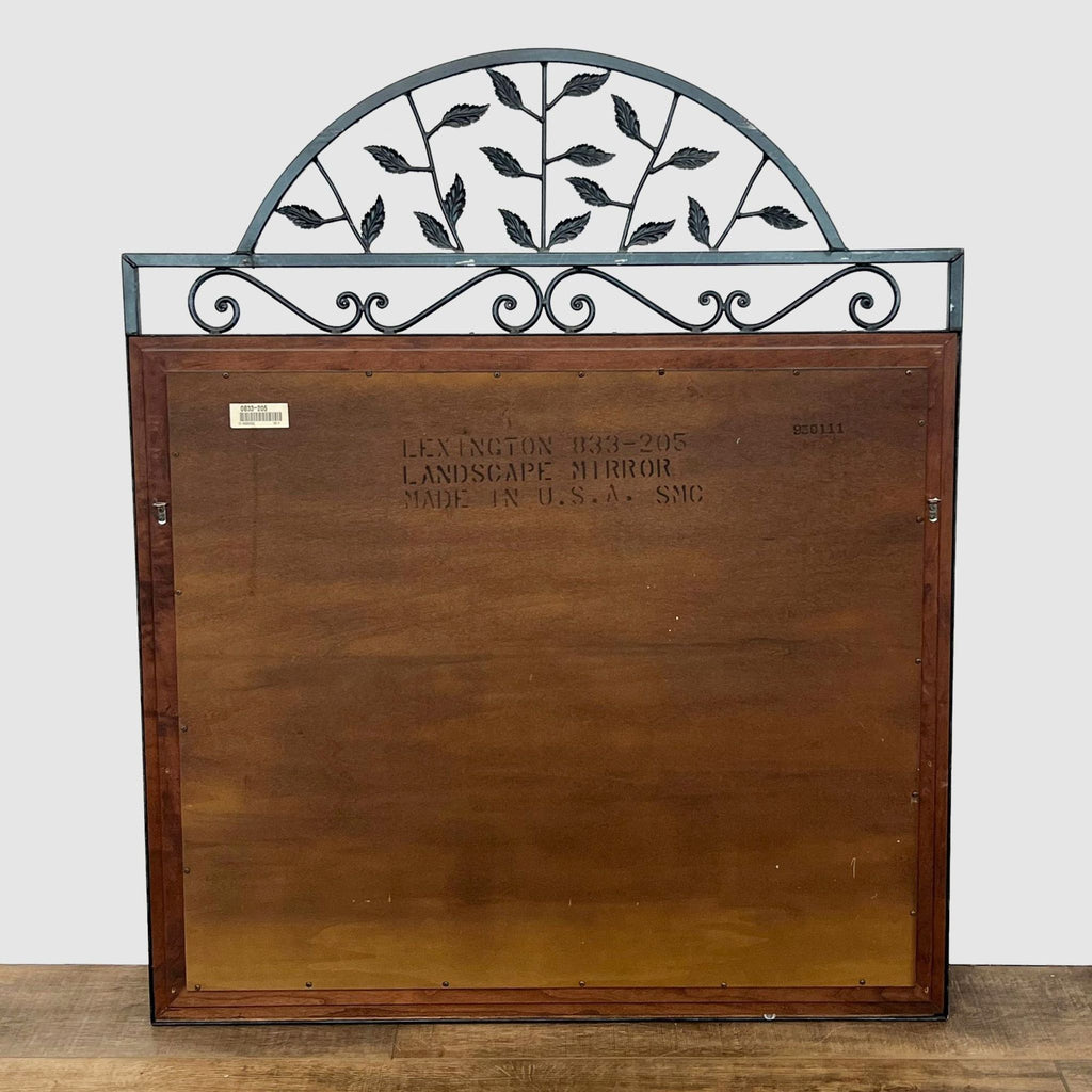 Back view of mirror with cherry wood frame and metal scroll detailing at the top.