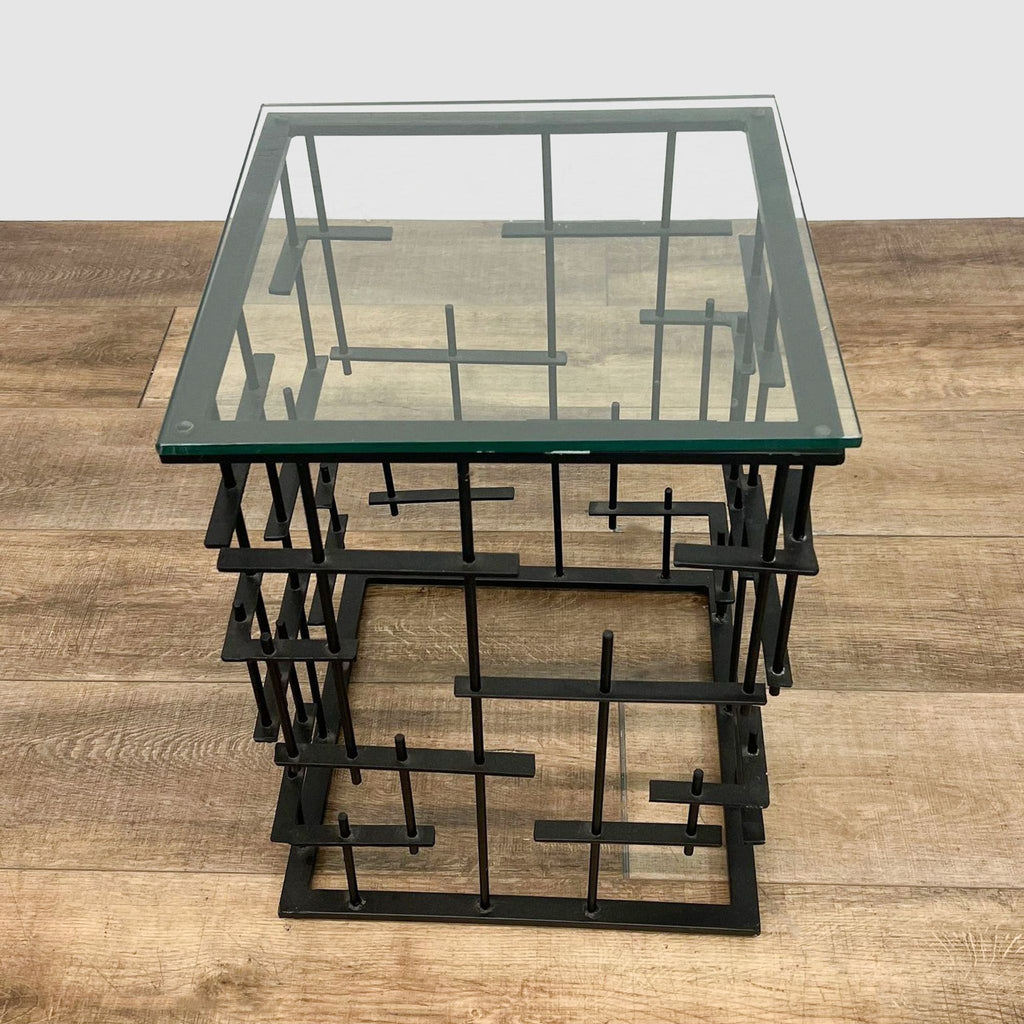 Front perspective of a Reperch side table with a clear glass top and intricate black metal support design.