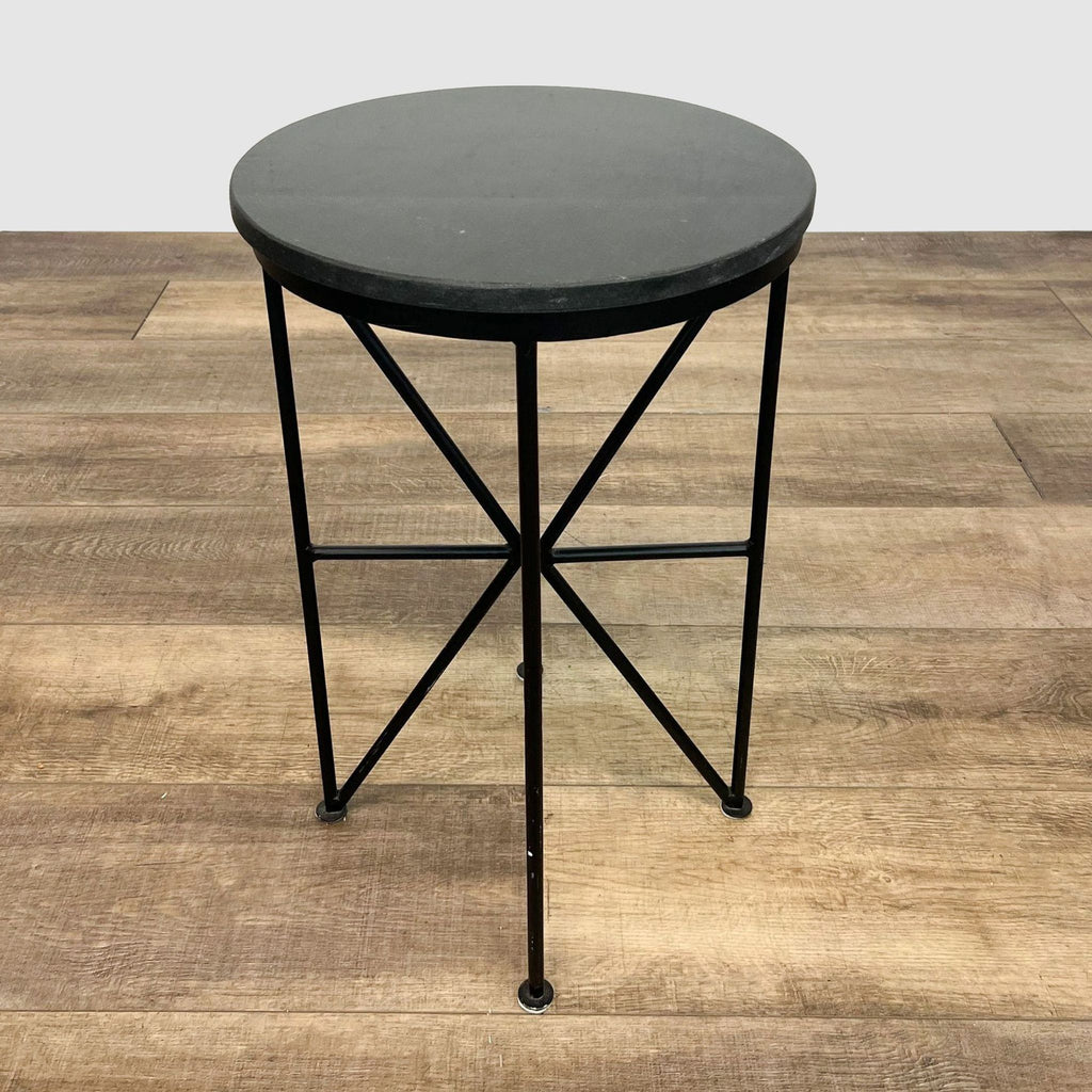 Reperch circular console table with black top and X-shaped iron legs on wooden floor.