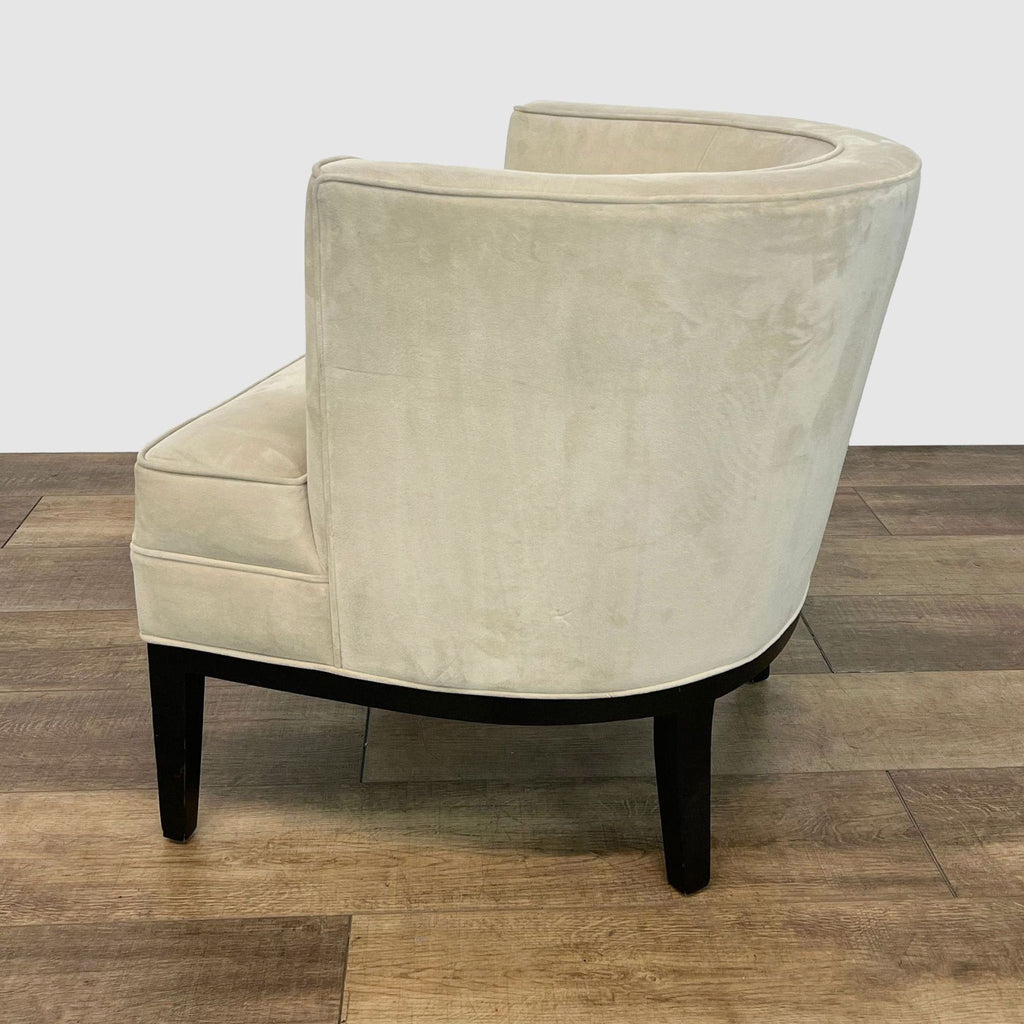 3. "Rear angle view of a cozy Reperch barrel back chair in velvet-like beige fabric with dark legs, on a wooden floor."