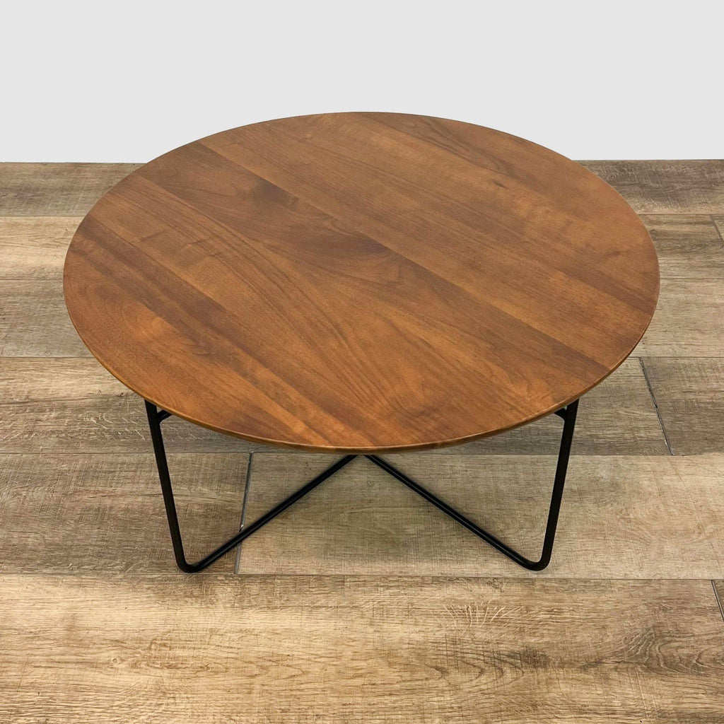 Round walnut wood coffee table by AllModern, Wadsworth model, on a wooden floor with a black metal base.