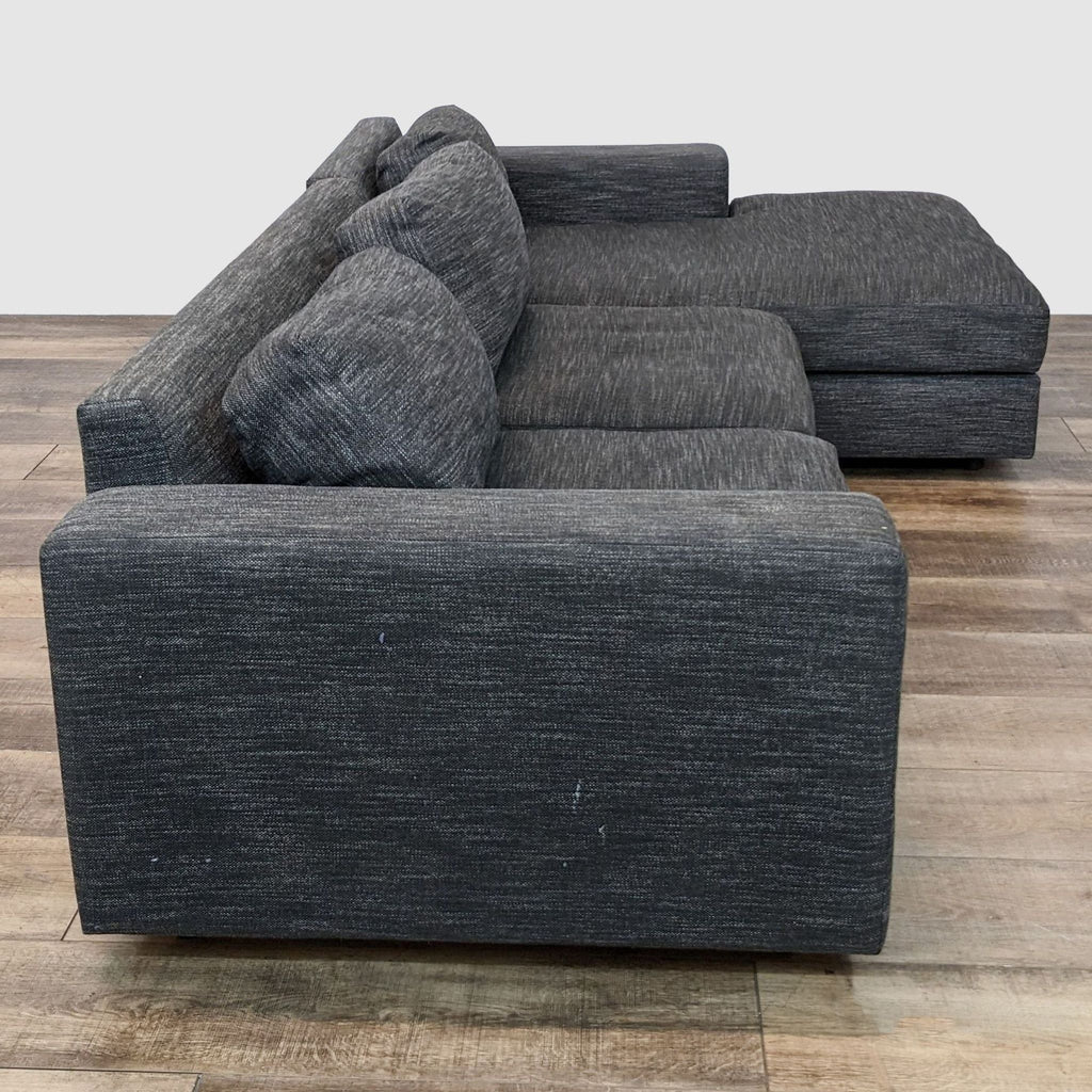 2. Side view of Urban sectional by West Elm featuring plush cushions and chaise in a gray tweed upholstery.