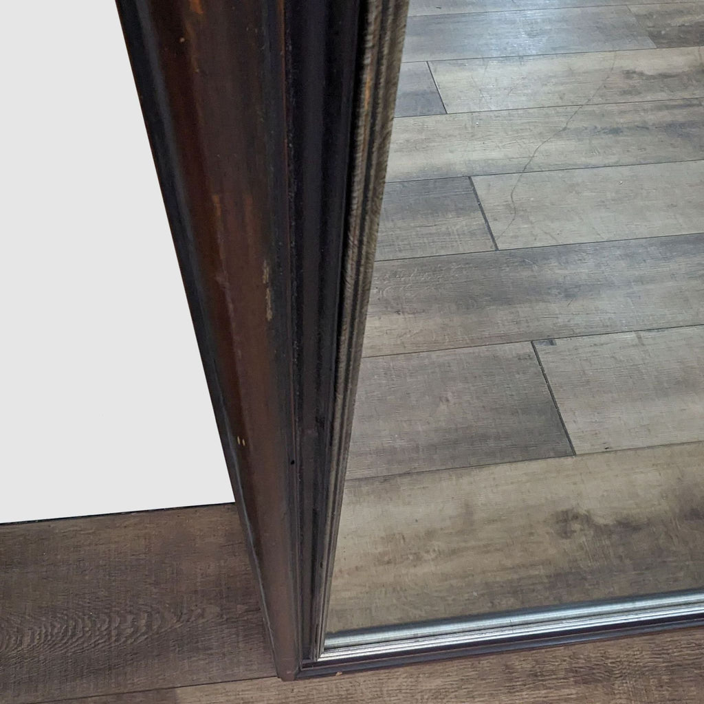 Close-up of the mirror's dark frame with gold accents.