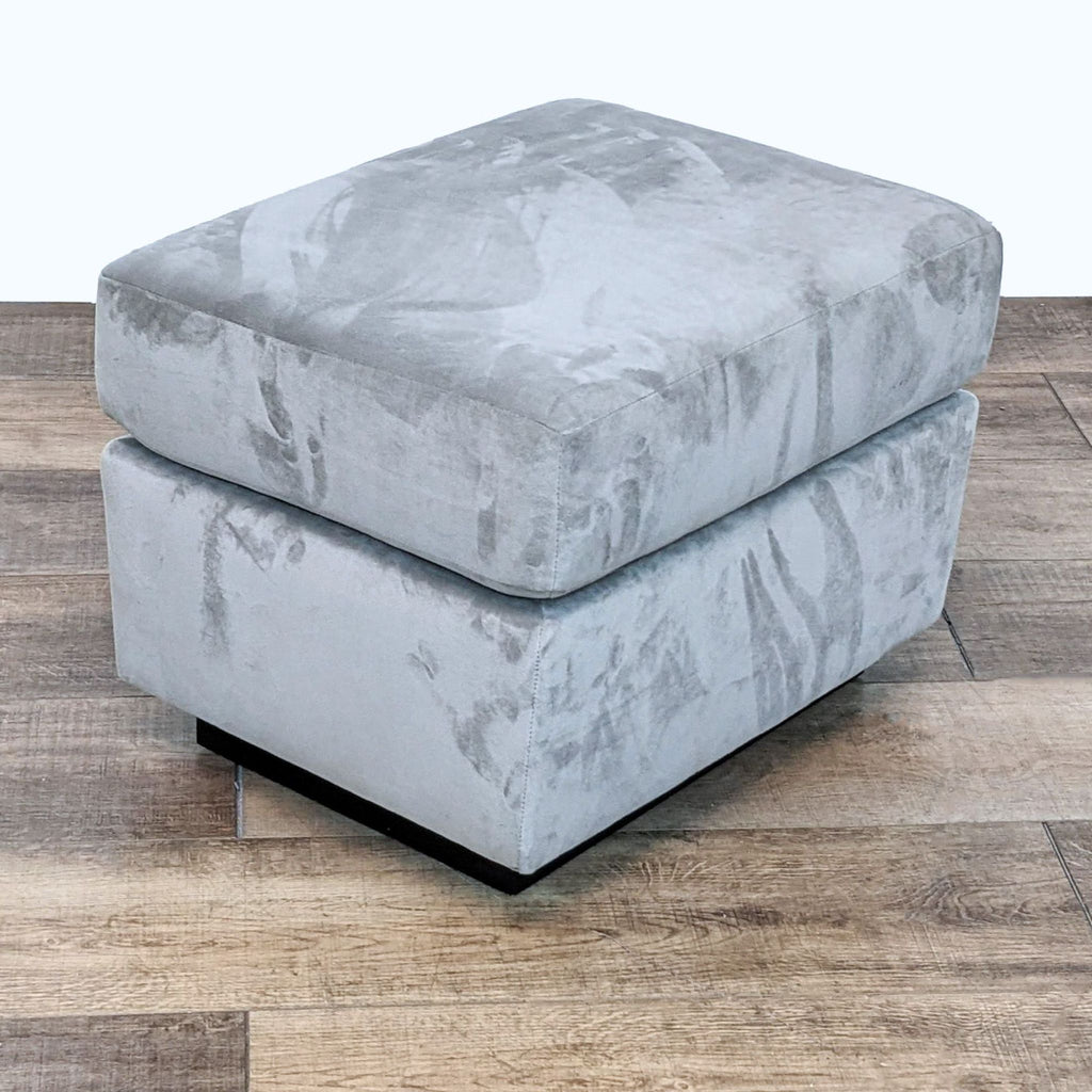 2. "Modern rectangular gray ottoman by West Elm on wooden floor, highlighting clean lines and texture."