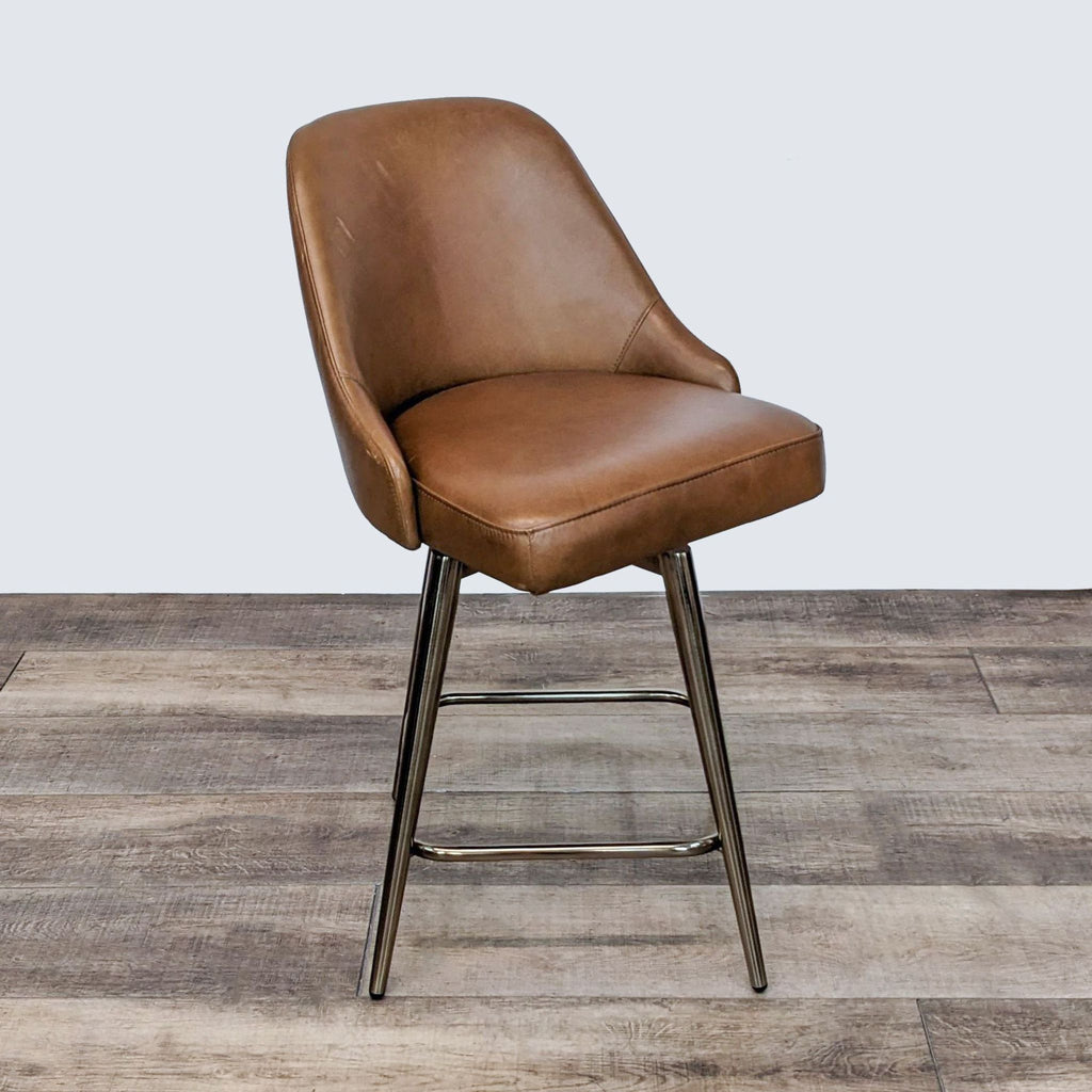 2. "360-degree swivel stool by West Elm featuring a brown leather cushioned seat and metal legs, on a wooden floor."