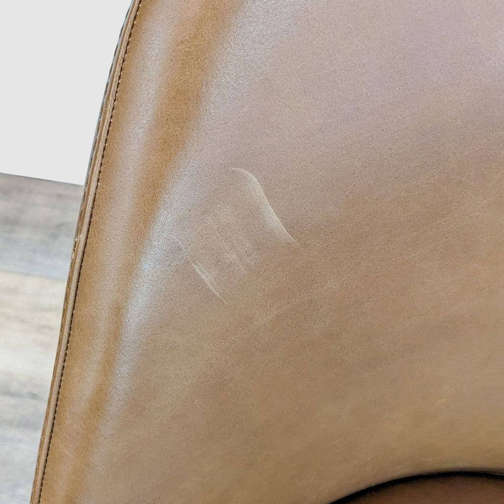 3. "Close-up of a brown leather upholstered seat from West Elm, highlighting the texture and stitching details."