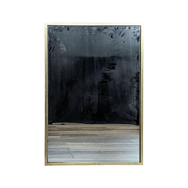 West Elm rectangle wall mirror with an antique brass metal frame on a wooden floor.