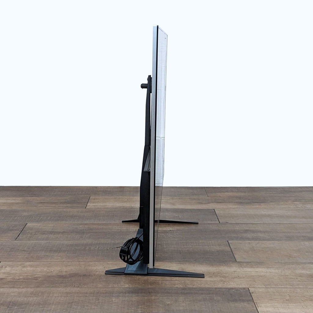 Side view of Samsung TV showing thin profile and stand, cables neatly tied.