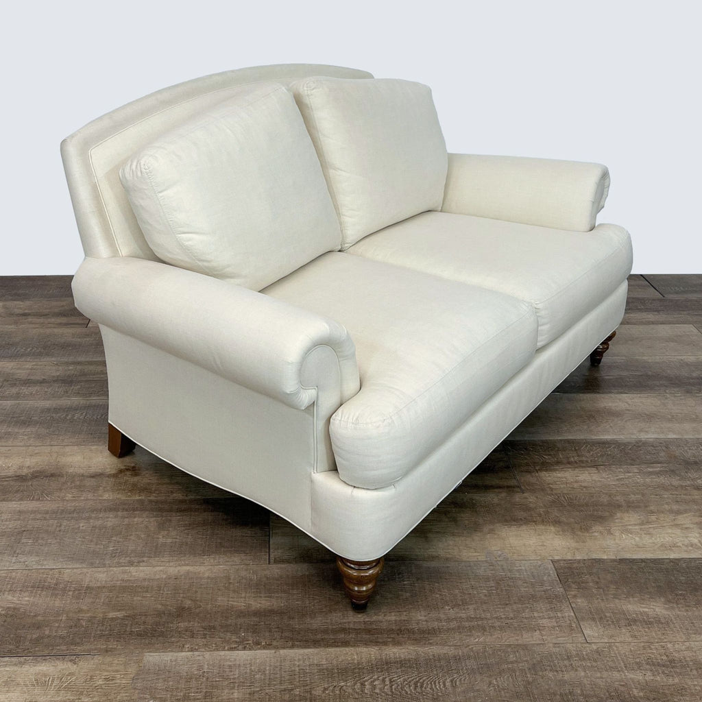Two-seater Ethan Allen loveseat in beige, shown at an angled view on wooden flooring.