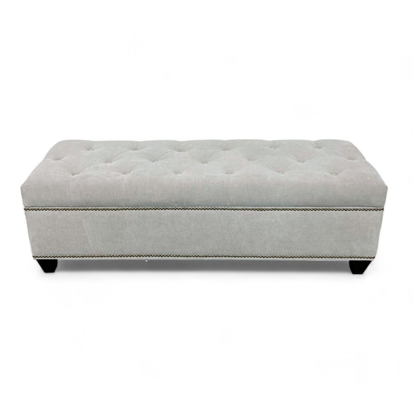 Neutral-colored upholstered storage ottoman with tufted cushion top.