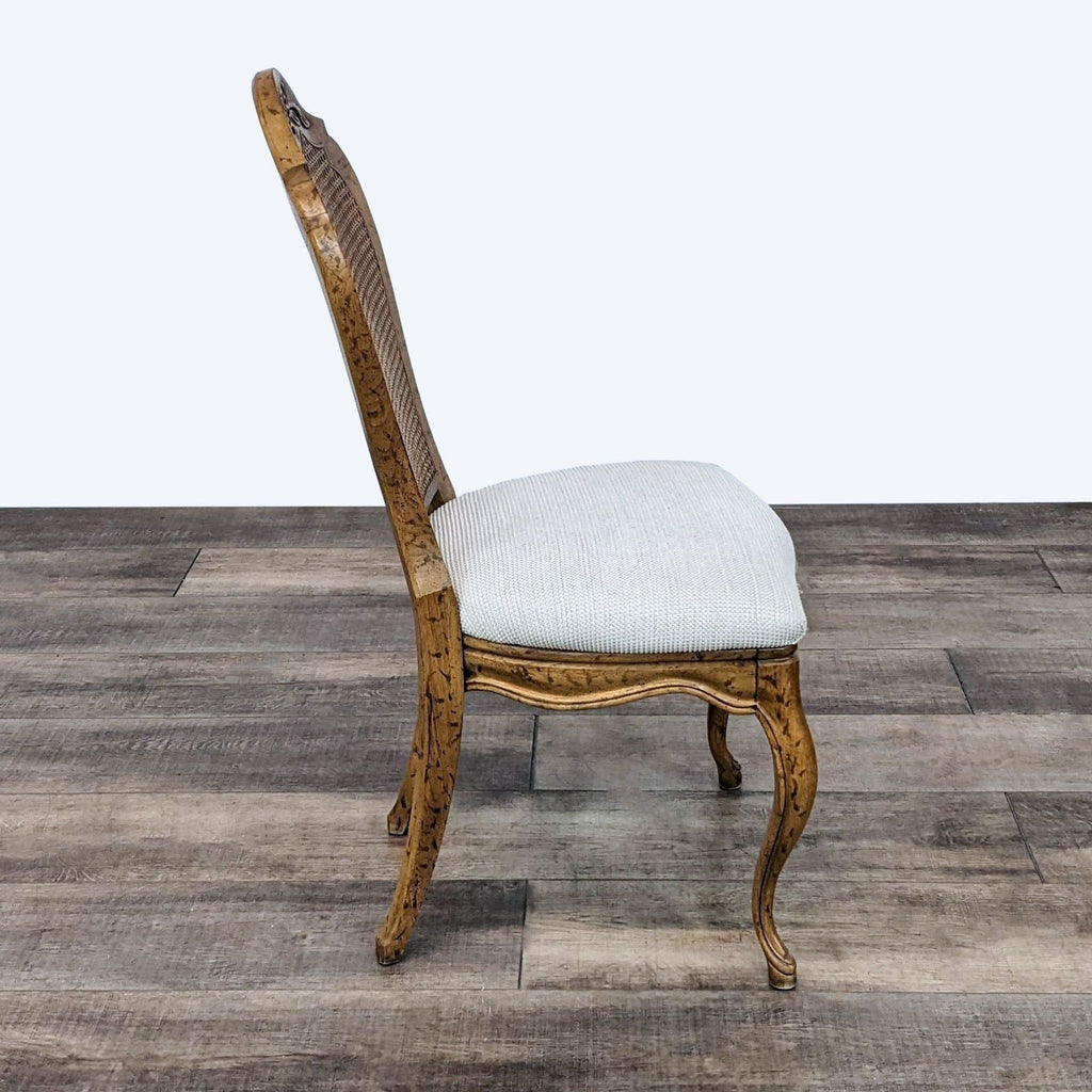 2. Side view of a Reperch Louis XV dining chair showing the cane back and curved wooden legs on a wood floor.